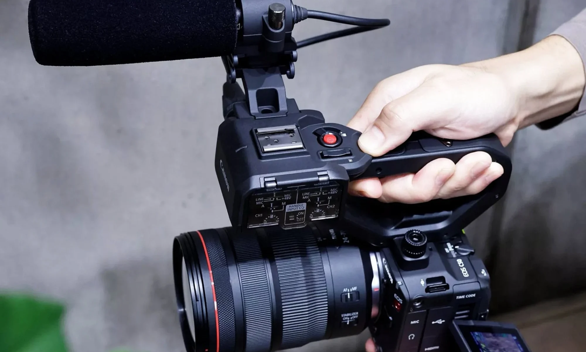 Кінокамера Canon EOS C50 чорного кольору зі встановленим об'єктивом Canon RF, мікрофоном-гарматою на верхній ручці та відкинутим зовнішнім дисплеєм.